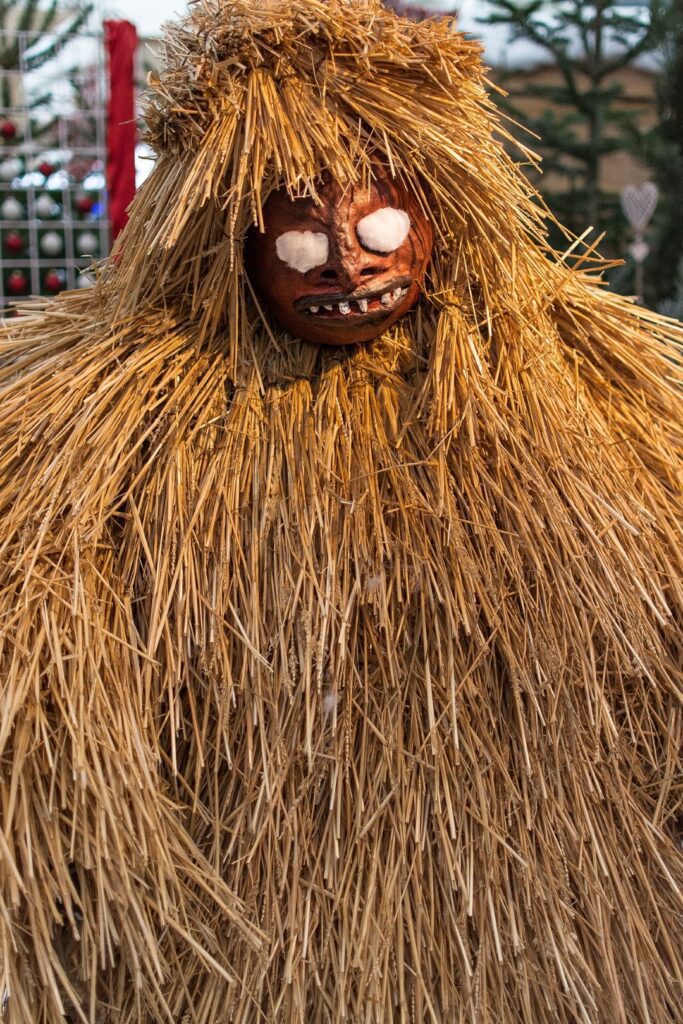 a buttnmandl (krampus) made of straw with white eyes 