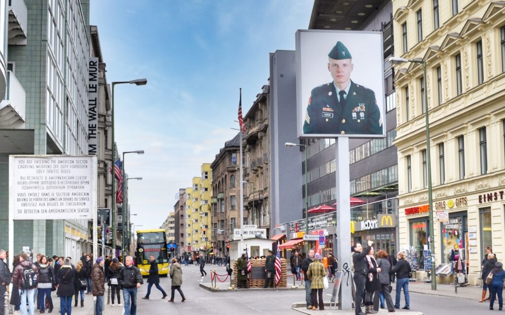 Checkpoint charlie in Berlin. Large picture of American soldier overlooks a square of tourists