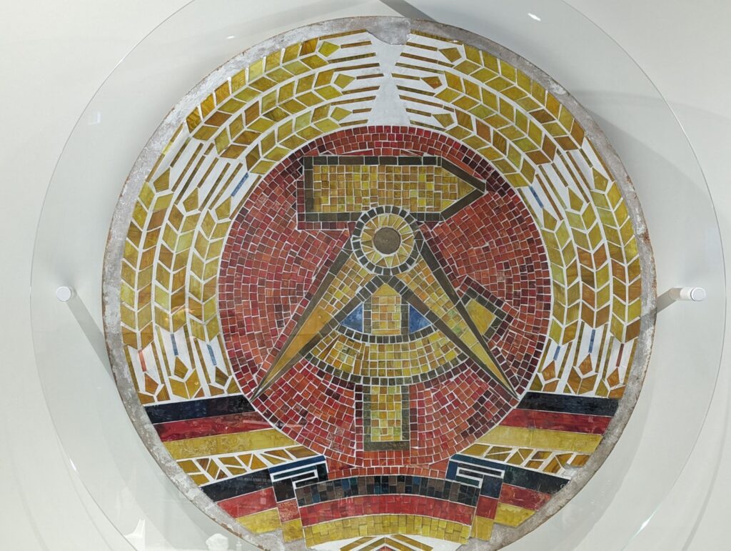 German mosiac symbol in the Berlin DDR museum showing the communist sickle and hammer in a mosaic made of the colors of the german flag black  red and yellow 