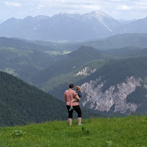 Mother holding toddler looking out over the mountains in South Germany