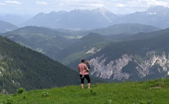 Mother holding toddler looking out over the mountains in South Germany